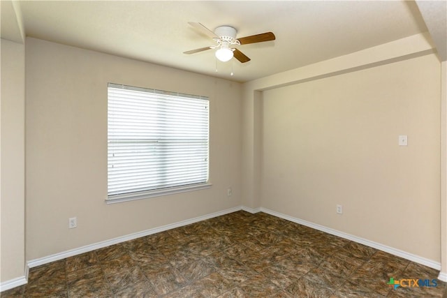 empty room with a ceiling fan and baseboards