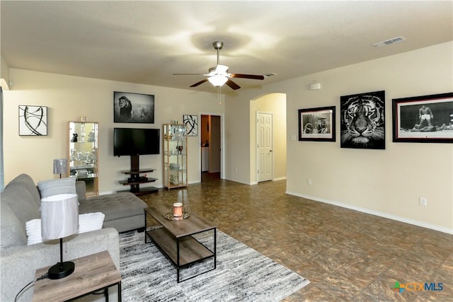 living room featuring visible vents, baseboards, a ceiling fan, and arched walkways