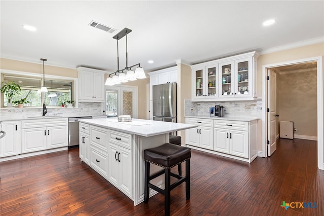 kitchen with dark wood-type flooring, a kitchen island, white cabinetry, and appliances with stainless steel finishes