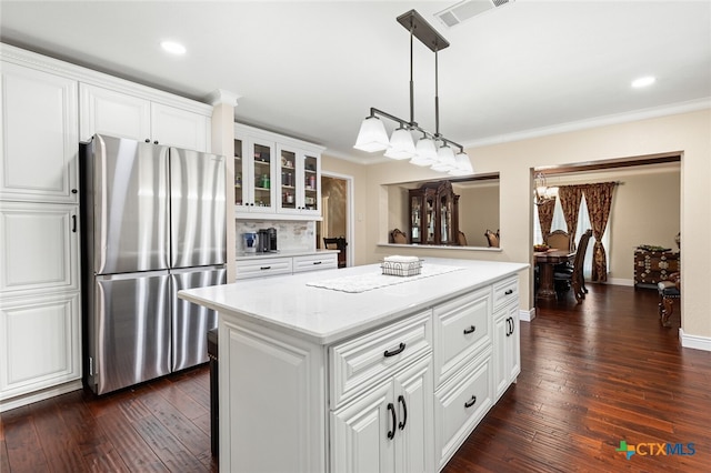 kitchen featuring dark hardwood / wood-style flooring, ornamental molding, stainless steel fridge, and white cabinets