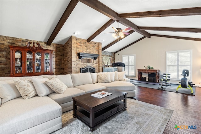 living room featuring hardwood / wood-style flooring, brick wall, ceiling fan, a fireplace, and lofted ceiling with beams