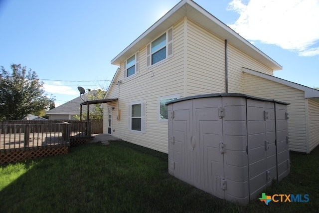 back of property featuring a lawn, a storage shed, and a deck