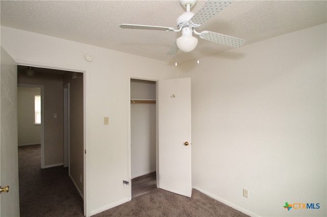 unfurnished bedroom featuring ceiling fan, a closet, dark carpet, and a textured ceiling