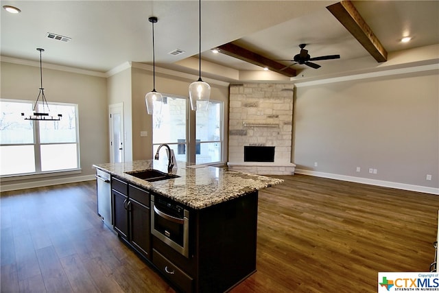 kitchen with dark wood-type flooring, hanging light fixtures, sink, and a center island with sink