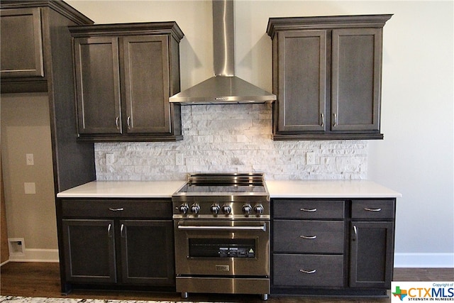 kitchen featuring stainless steel range, dark brown cabinets, decorative backsplash, and wall chimney exhaust hood