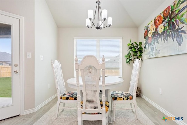 dining area featuring light wood-type flooring, vaulted ceiling, and a notable chandelier