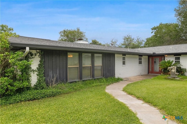1223 N Sarah Dewitt Dr, Gonzales, TX 78629 - back of property featuring a lawn, a chimney, brick siding, and a shingled roof