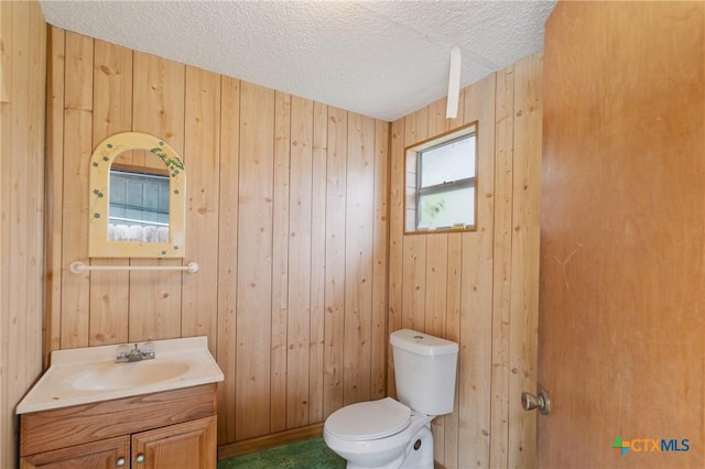 1223 N Sarah Dewitt Dr, Gonzales, TX 78629 - half bath featuring toilet, vanity, a textured ceiling, and wooden walls