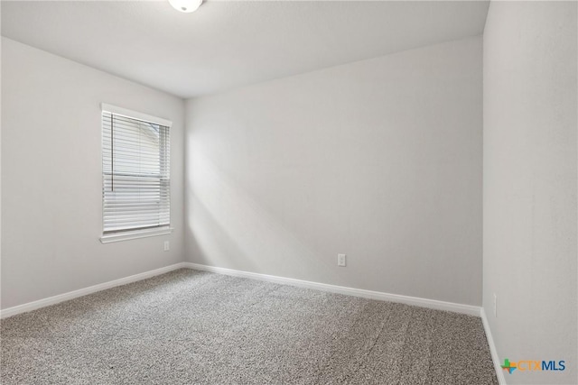 carpeted empty room featuring baseboards
