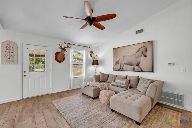 living room with ceiling fan, vaulted ceiling, and light hardwood / wood-style floors