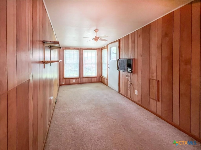 unfurnished living room with light carpet, ceiling fan, wooden walls, and an AC wall unit