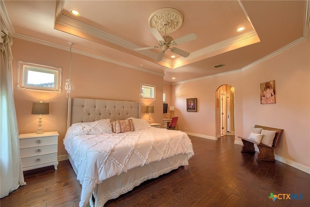 bedroom featuring arched walkways, a raised ceiling, and dark wood finished floors