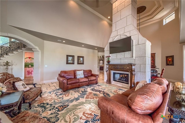 living area featuring baseboards, a high ceiling, ornamental molding, and a tile fireplace