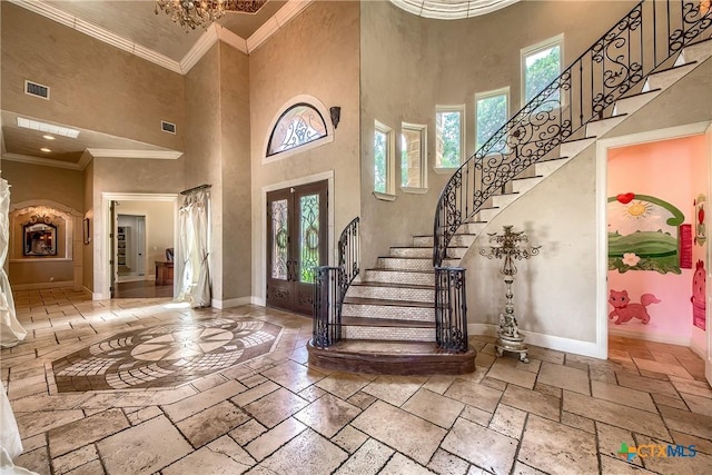 entrance foyer featuring french doors, stone tile floors, stairway, ornamental molding, and baseboards