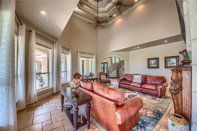 living room featuring crown molding, a healthy amount of sunlight, stairs, and stone tile floors