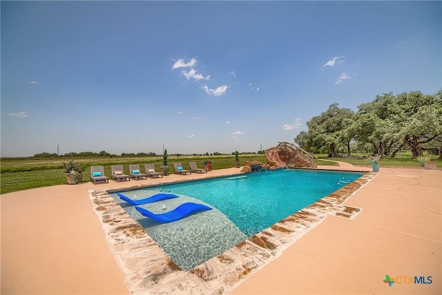 outdoor pool with a water slide and a patio