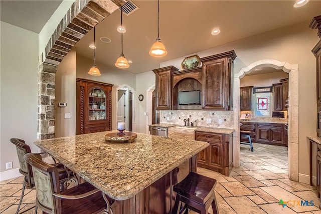 kitchen with arched walkways, pendant lighting, and a center island