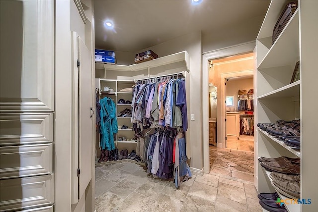 walk in closet featuring stone tile flooring