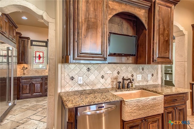 kitchen with a sink, light stone counters, stainless steel appliances, and stone tile flooring