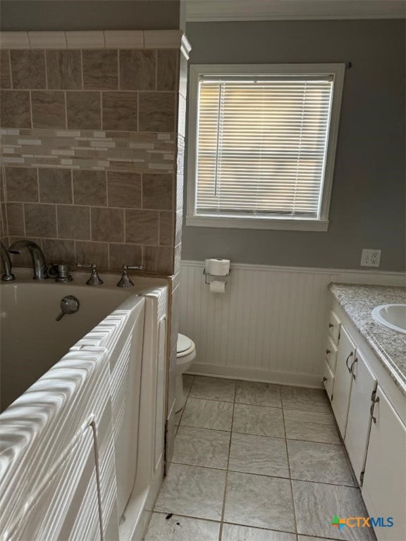 bathroom featuring tile patterned flooring, vanity, a bathing tub, and toilet