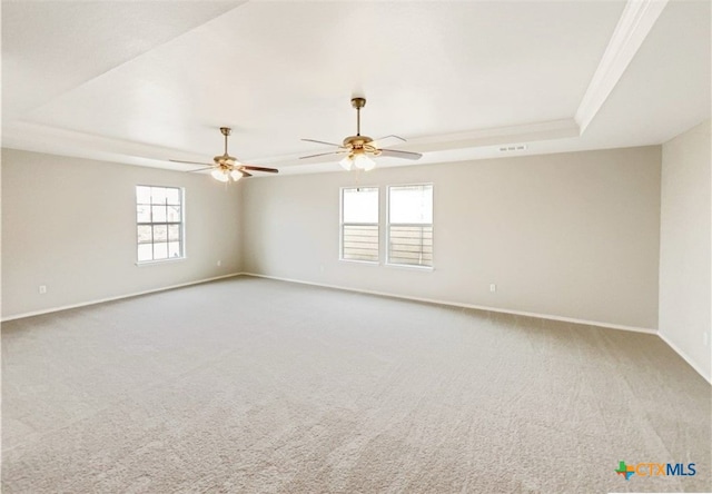 carpeted empty room with ornamental molding, ceiling fan, and a raised ceiling