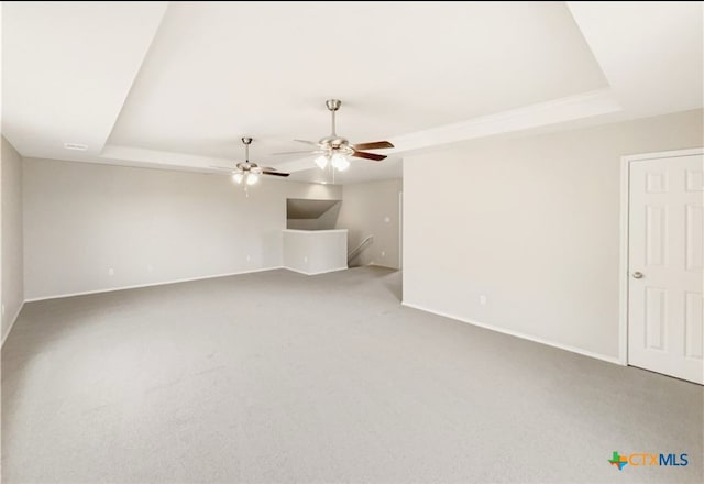 carpeted spare room featuring ceiling fan and a raised ceiling