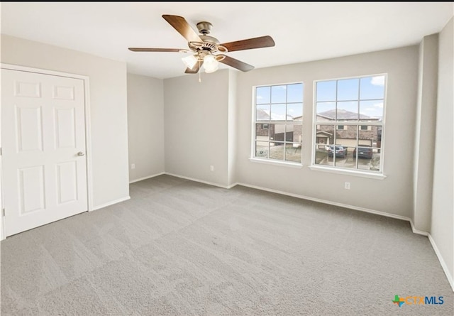 carpeted spare room featuring ceiling fan