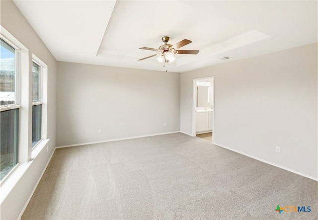 carpeted empty room with ceiling fan and a raised ceiling