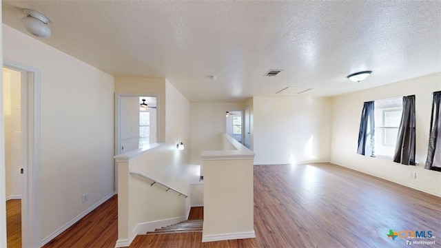 unfurnished room featuring ceiling fan, wood-type flooring, and a textured ceiling