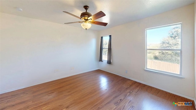 empty room featuring plenty of natural light, ceiling fan, and wood-type flooring