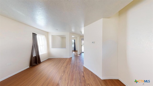 unfurnished room featuring a textured ceiling and light wood-type flooring