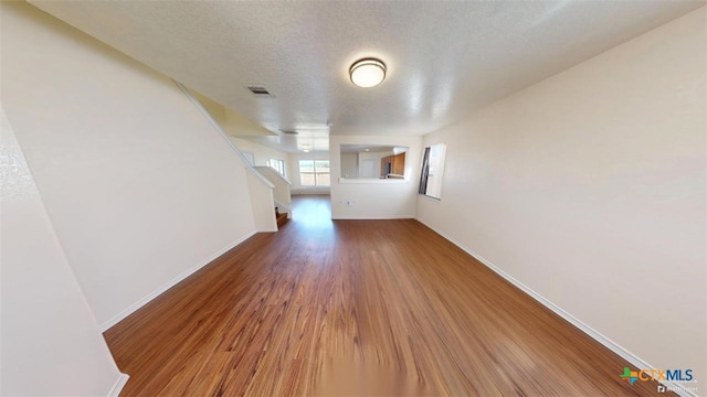 unfurnished living room featuring hardwood / wood-style flooring and a textured ceiling