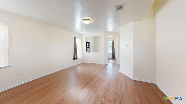 unfurnished room with wood-type flooring and a textured ceiling