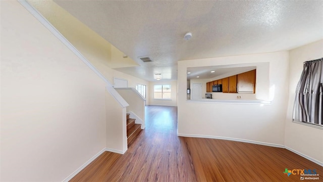 unfurnished living room featuring hardwood / wood-style floors and a textured ceiling