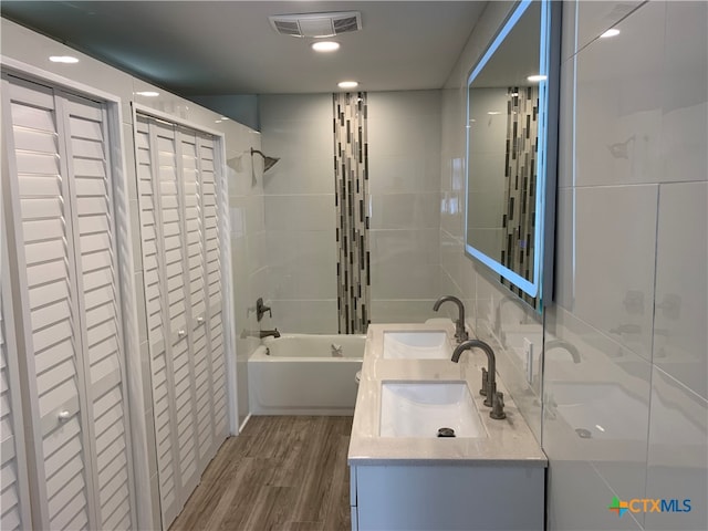 bathroom featuring wood-type flooring, vanity, and tiled shower / bath