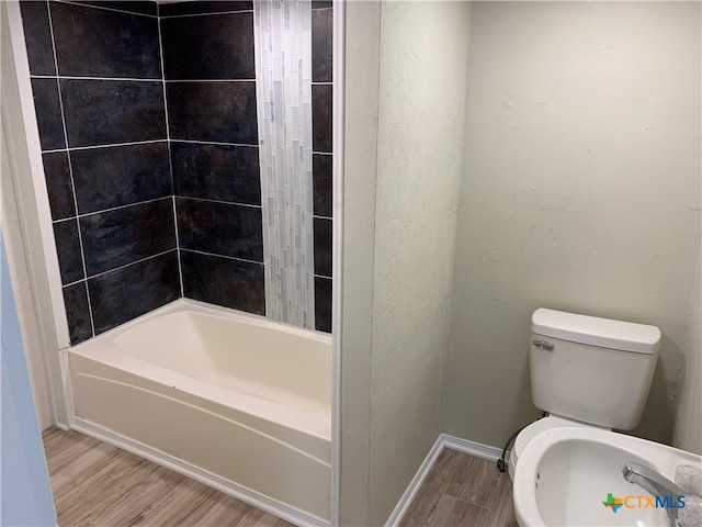 bathroom featuring toilet, tiled shower / bath, and hardwood / wood-style floors