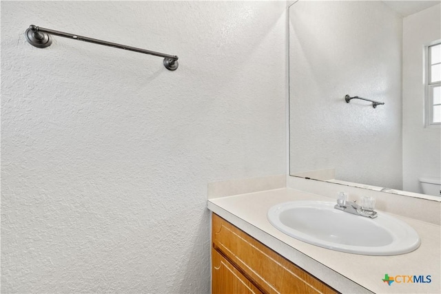 bathroom featuring a textured wall and vanity