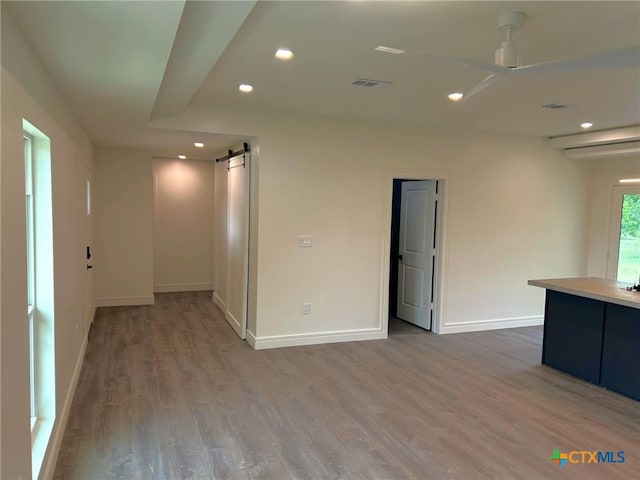 unfurnished room with a barn door, recessed lighting, wood finished floors, baseboards, and ceiling fan