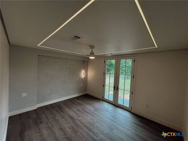 spare room featuring wood finished floors, visible vents, baseboards, and french doors