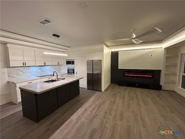 kitchen with a sink, light countertops, white cabinets, appliances with stainless steel finishes, and visible vents