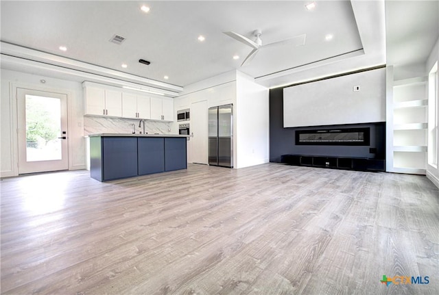 3104 Zephyr Rd, Killeen, TX 76543 - unfurnished living room with light wood-style flooring, recessed lighting, a sink, ceiling fan, and a glass covered fireplace