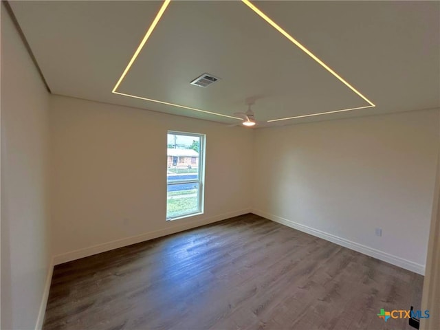 unfurnished room featuring baseboards, wood finished floors, visible vents, and a ceiling fan