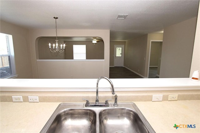kitchen featuring a textured ceiling, visible vents, light countertops, a sink, and a notable chandelier