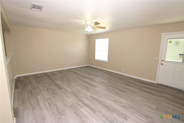 spare room featuring baseboards, a textured ceiling, a ceiling fan, visible vents, and wood finished floors