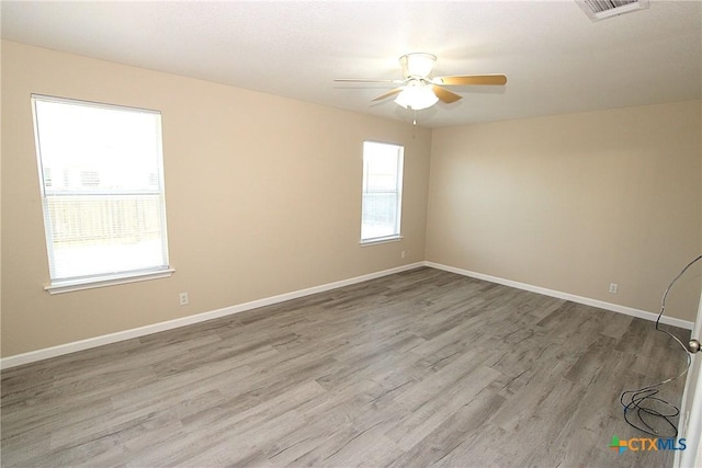 unfurnished room featuring wood finished floors, ceiling fan, baseboards, and plenty of natural light