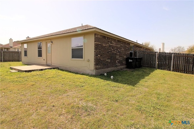 rear view of house featuring a yard, a fenced backyard, a patio area, and brick siding