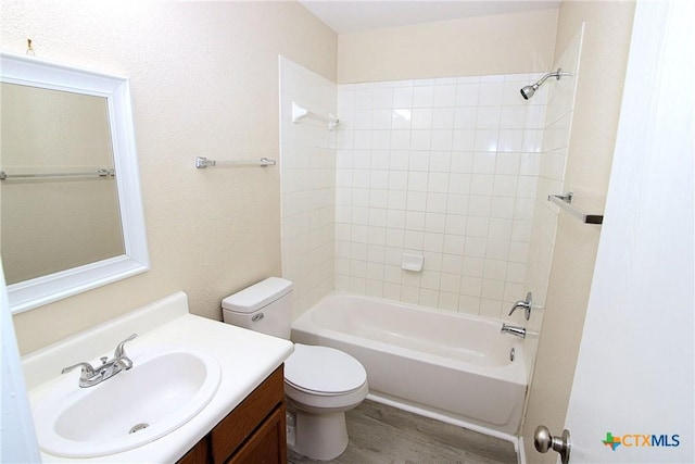 full bathroom featuring toilet, wood finished floors, vanity, and bathtub / shower combination