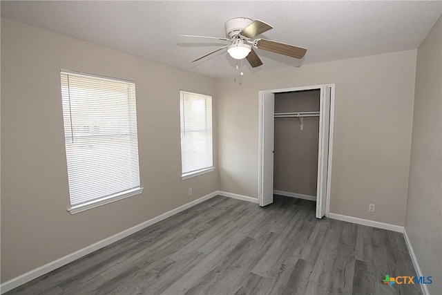 unfurnished bedroom with a closet, baseboards, a ceiling fan, and wood finished floors