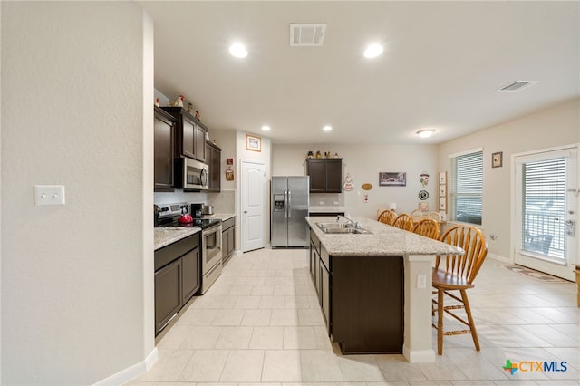 kitchen featuring sink, stainless steel appliances, tasteful backsplash, a kitchen island with sink, and a breakfast bar