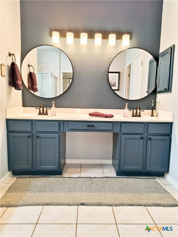 bathroom featuring tile patterned flooring, vanity, and a shower with door